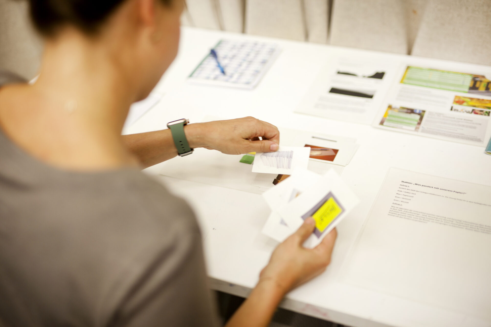 Eine Fachkraft ordnet Bilder mit Papiersorten den verschiedenen Mülltonnen zu